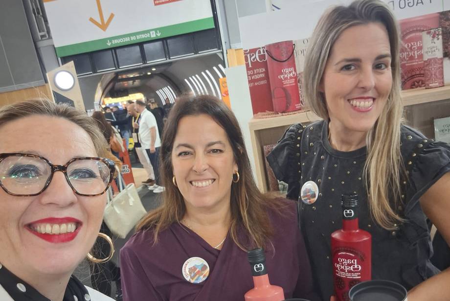 Tres socias de Mujeres en Gastronomía sonríen junto a botellas de aceite Pago de Espejo en la feria SIAL París 2026